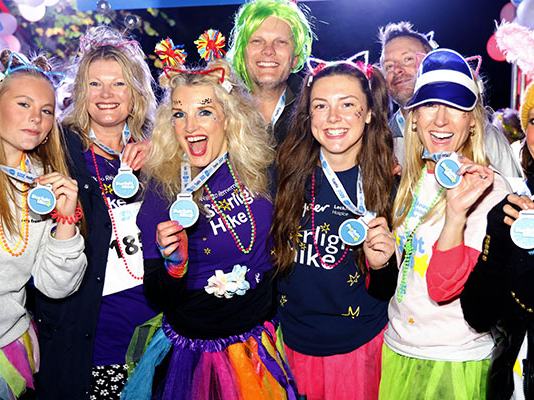A group of Starlight Hike walkers in bright neon clothing and lights