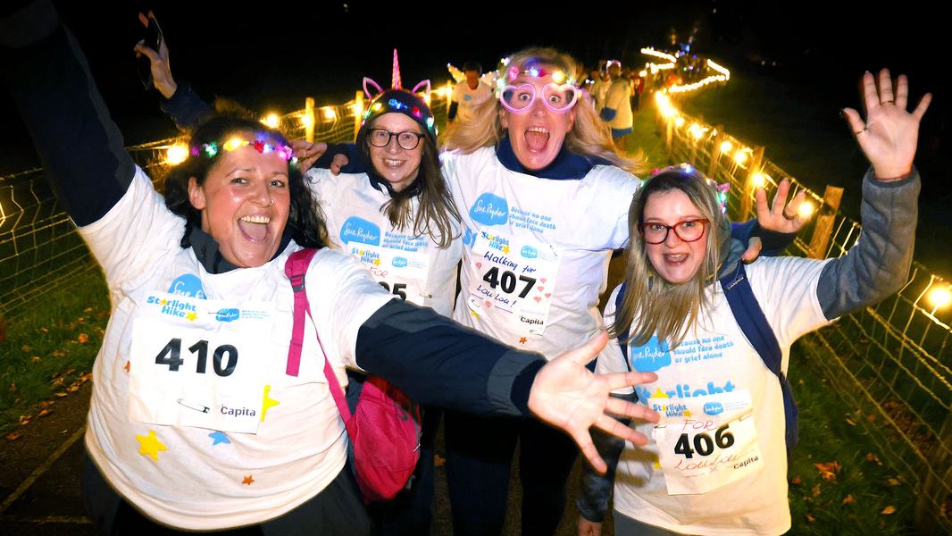 A group of Starlight Hike walkers in bright neon clothing, with the light trail glowing behind them