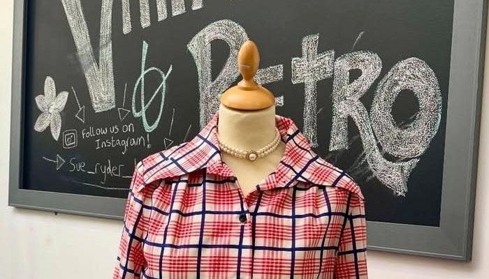 A vintage dress on a stand, in front of a blackboard saying 'Sue Ryder Bedford - Vintage and Retro'