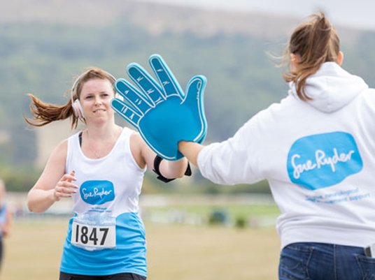 A Sue Ryder runner giving a fundraising volunteer a high five at a cheer point