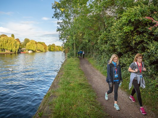 Walkers going along the Thames path route, with the river to their left