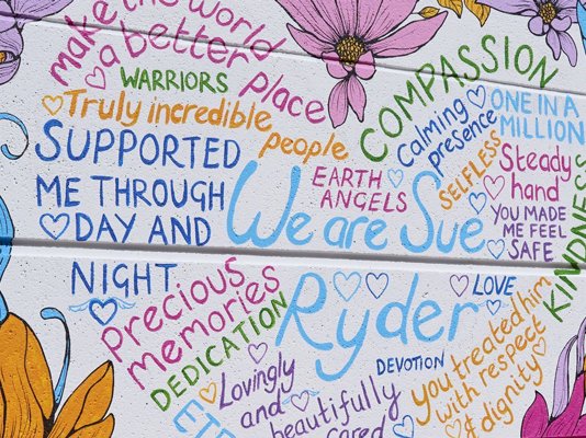 The 'We are Sue Ryder' mural with flower decorations