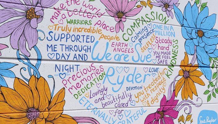 The 'We are Sue Ryder' mural with flower decorations