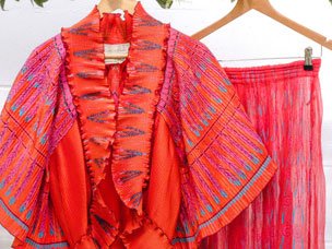 A red Zara Rhodes top and trouser outfit, hanging up under a flower arch