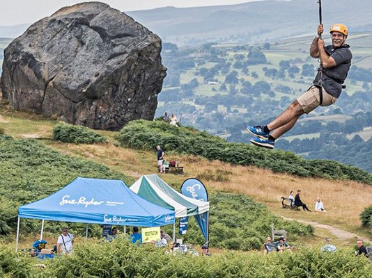 A person zip wiring down from The Cow rocks