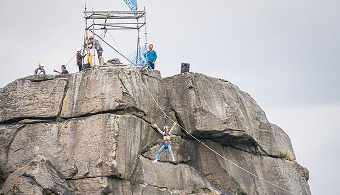 A person zip wiring down from the top of The Cow rocks
