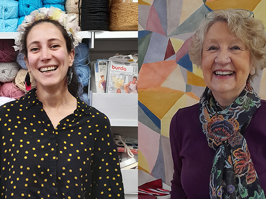 Two smiling volunteers in front of brightly coloured shop displays