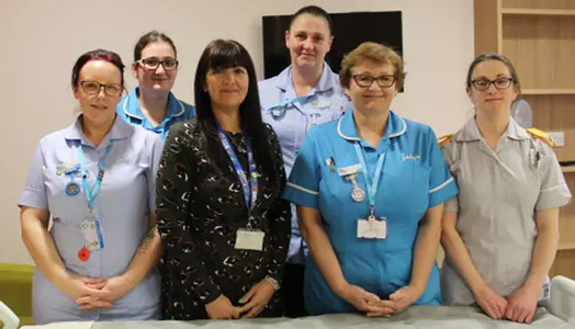 Photo of a BGL employee standing and smiling with Sue Ryder healthcare staff