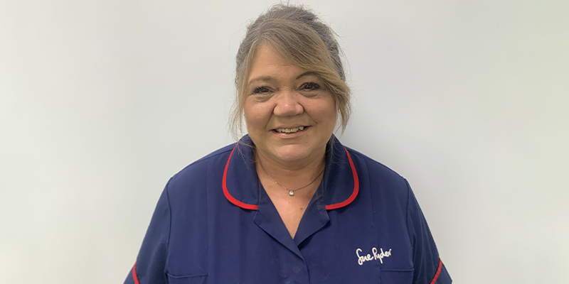 Bobby smiles, wearing her dark blue Sue Ryder nurses uniform.