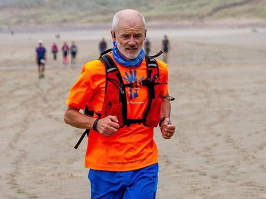 David running across a sandy beach.