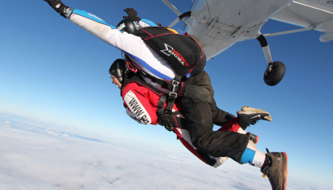 Image of two people jumping out of a plane in a tandem skydive