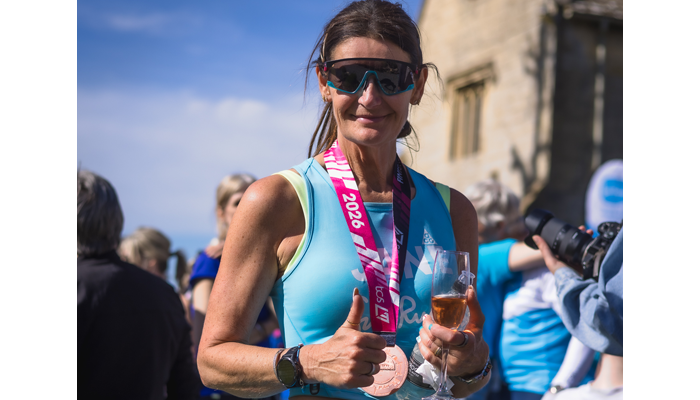 Jane posing with a glass of champagne after completing her London Marathon and 100-miles run back