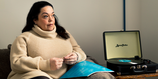 Lisa Riley thoughtfully looking to the side, next to a record player
