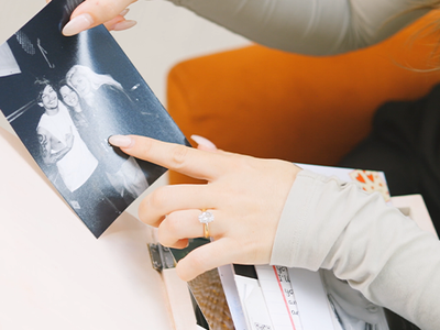 Close up of Lottie's hands, looking at photo of herself, her brother and mum