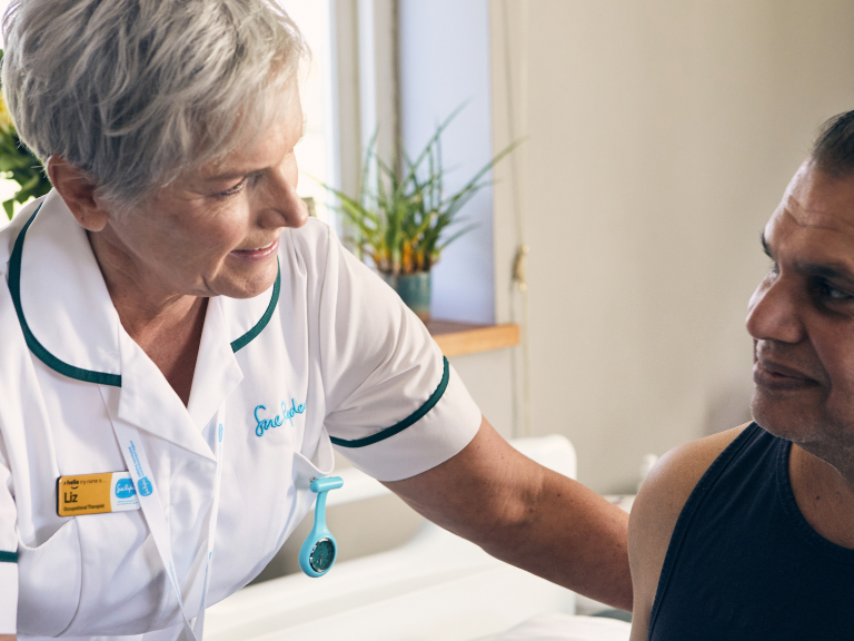 Occupational therapist in white uniform cares for man lying in bed