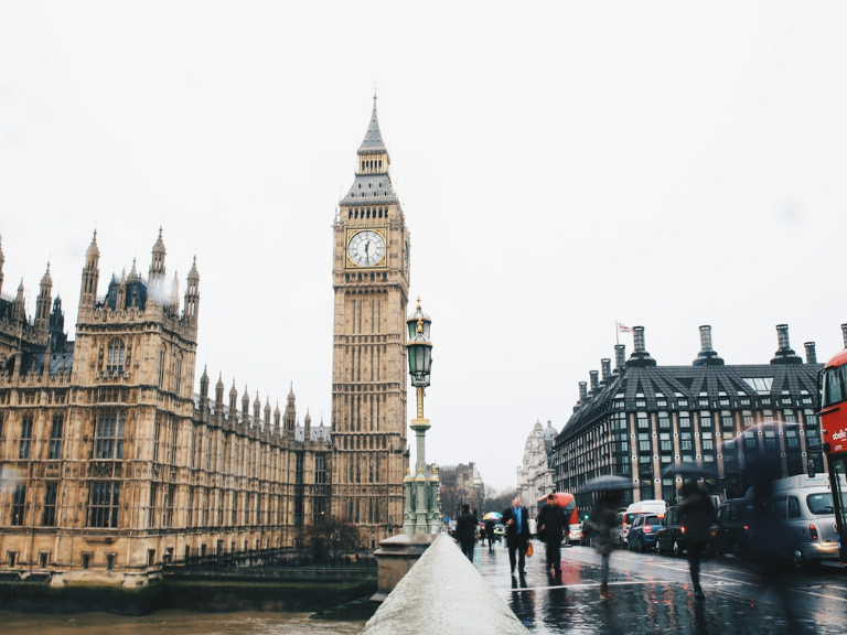 The Houses of Parliament and Big Ben, with people and traffic going past on the street
