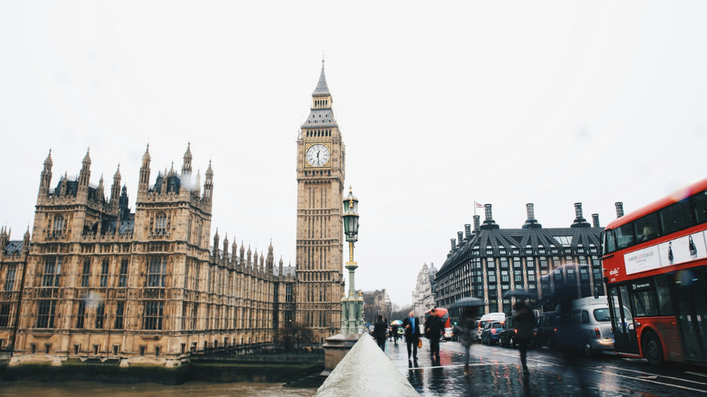 The Houses of Parliament and Big Ben, with people and traffic going past on the street