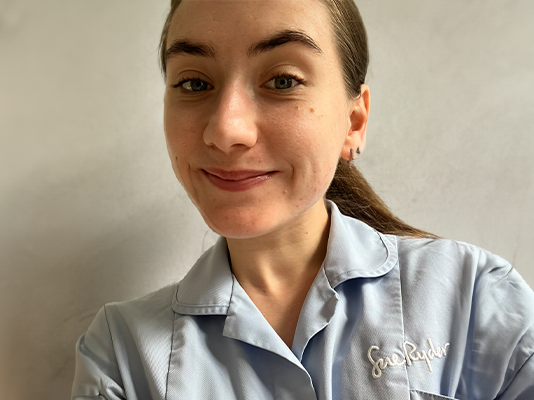 Olivia takes a selfie in her pale blue Sue Ryder uniform.