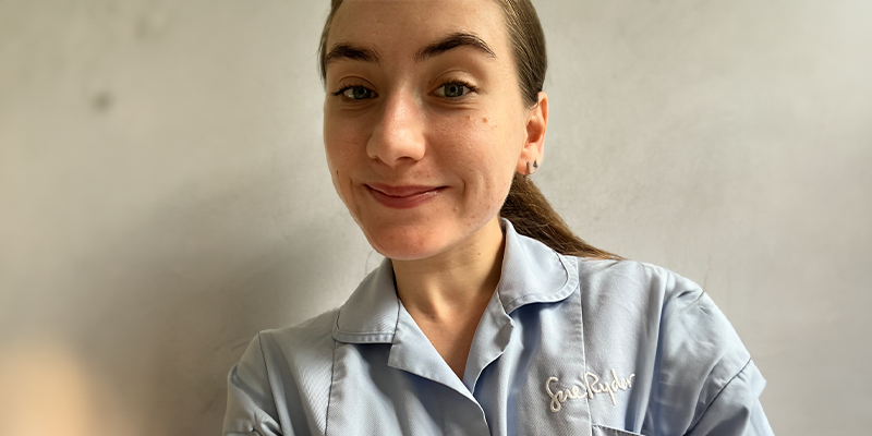 Olivia takes a selfie in her pale blue Sue Ryder uniform.