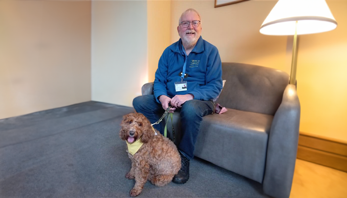 Richard sits holding Jack the cockapoo's lead
