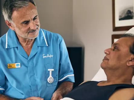 A Sue Ryder Nurse giving medication to a patient, with their partner in the foreground